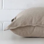 Linen stone cushion laying on its side. It has a square size.