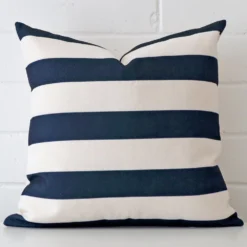 Linen cushion cover features prominently against a white wall. It is a square design and has a striped decorative finish.