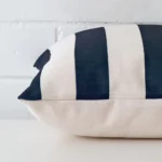 Striped cushion cover laid on its back side. The image shows a side-on view of the linen material and its square dimensions.