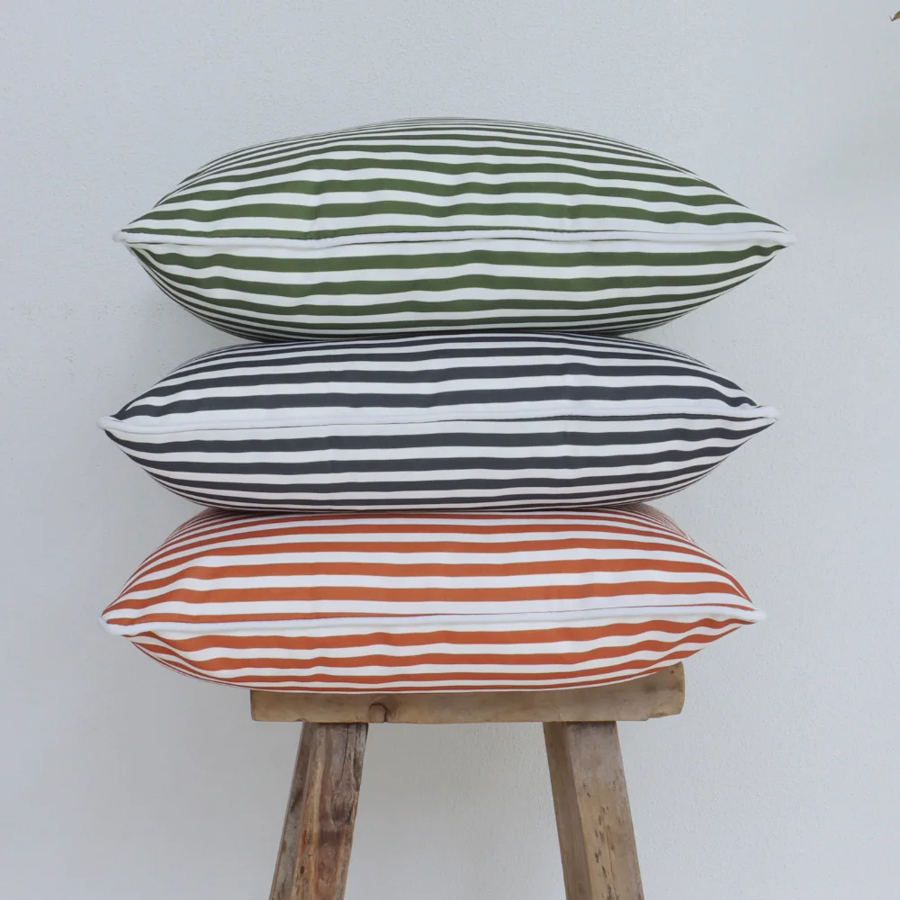 Three striped outdoor cushions arranged in an elegant stack outside.