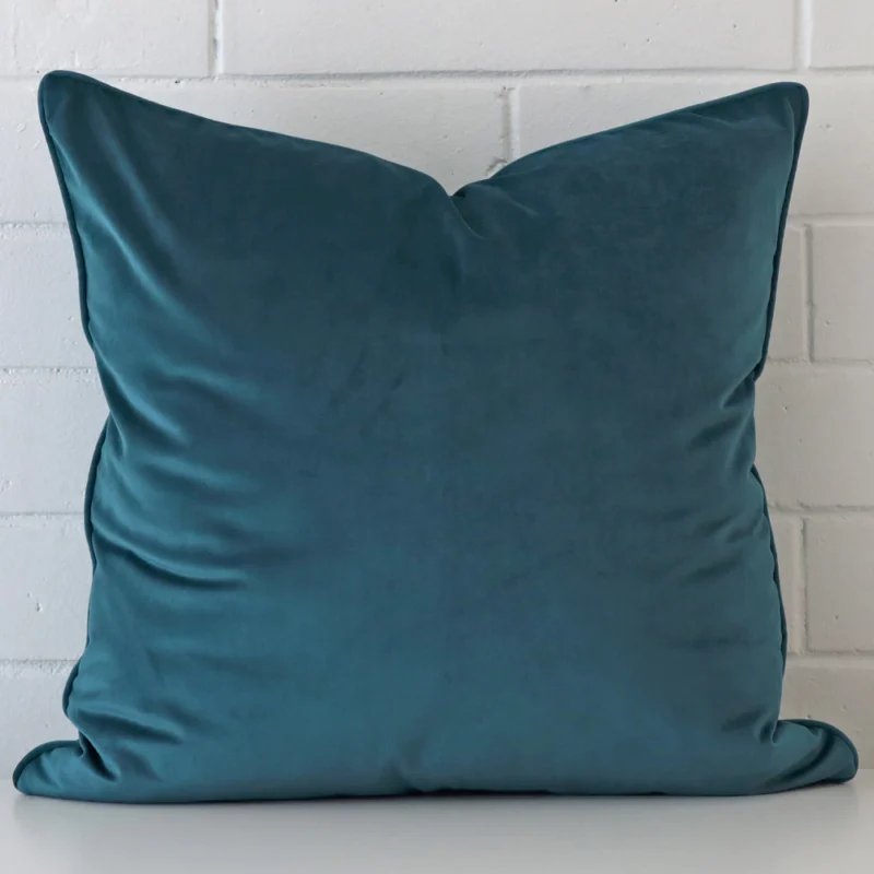 teal-velvet-cushion-cover-55cm-x-55cm-sc430-55b An attractive velvet cushion in front of a white brick wall. It has a large size and is teal in colour.