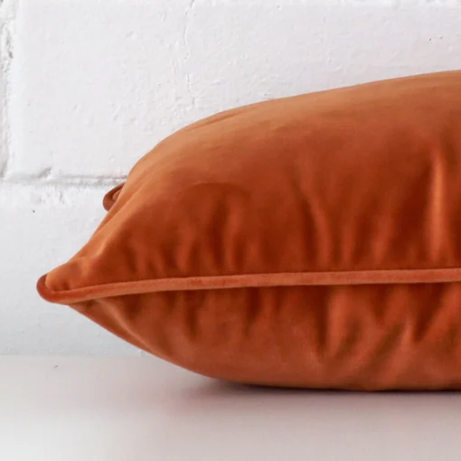 Rectangle cushion cover in terracotta colour sitting flat. The sideways viewpoint shows the seams of the velvet material.