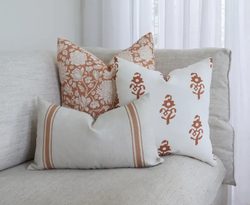 Three cushions arranged at the end of light coloured seating.