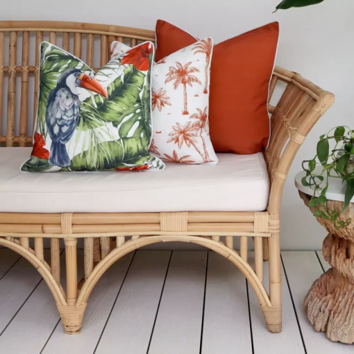 A set of 3 tropical terracotta outdoor couch cushions is displayed on a corner of a rattan seat.