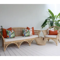 Seven terracotta cushions on an outdoor sofa surrounded by lush green plants offering a cozy vibe.