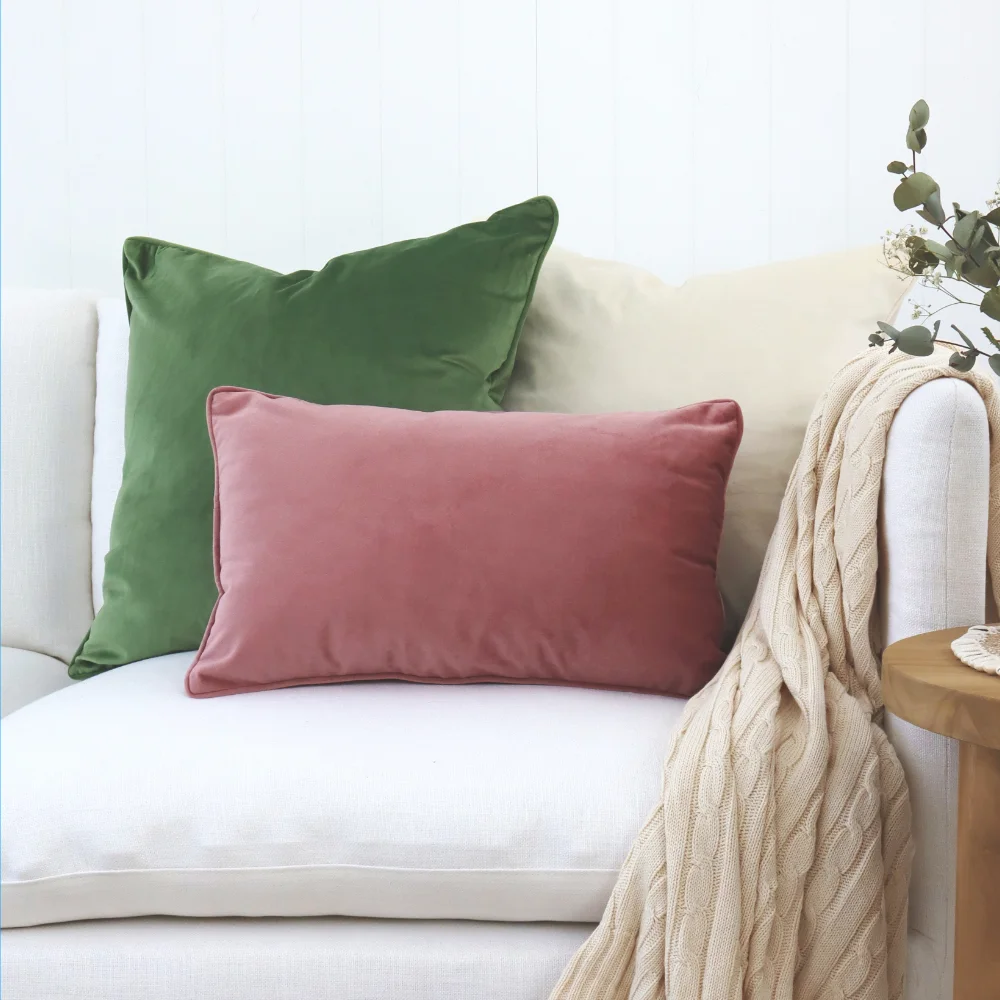 Three velvet cushions tastefully arranged on elegant light seating.