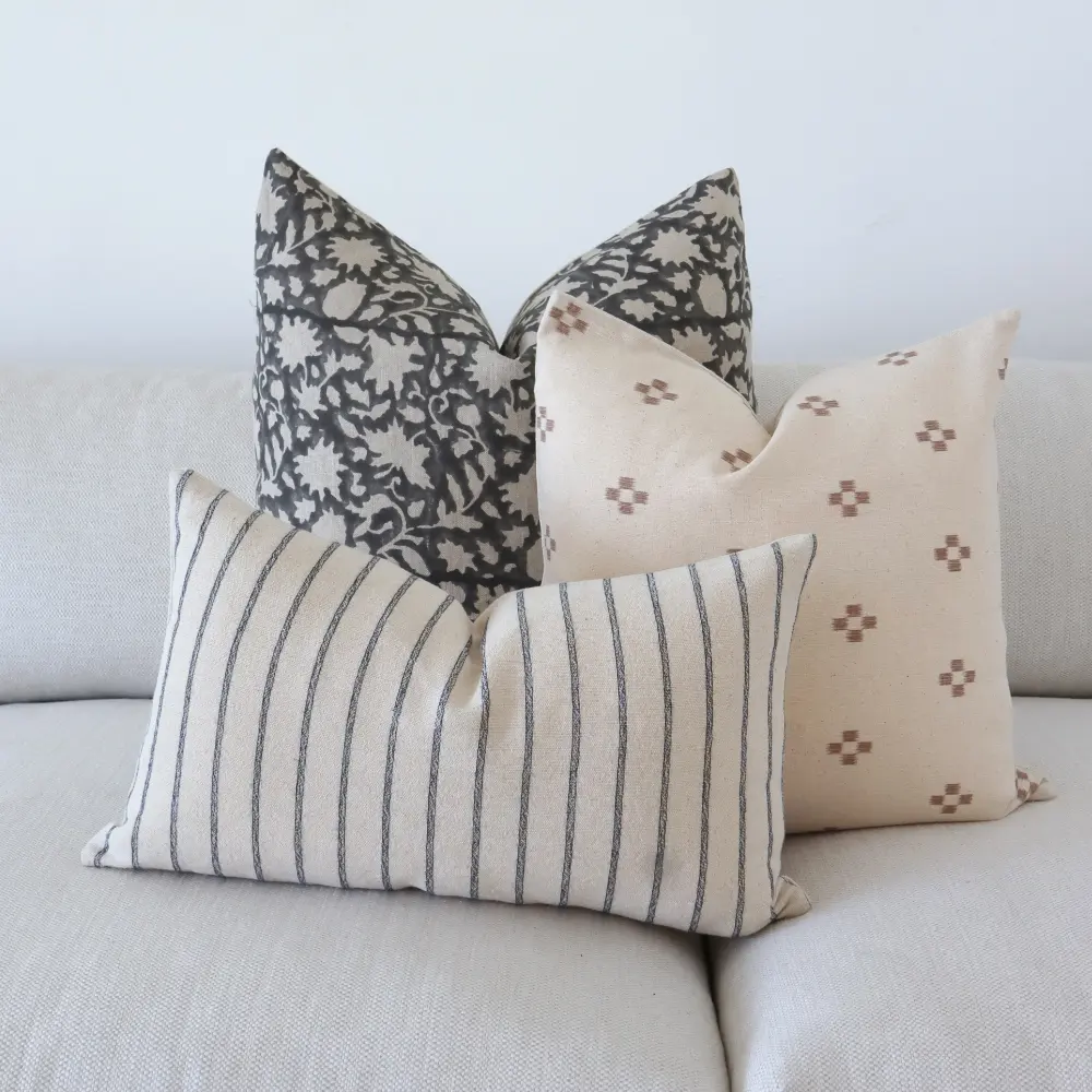 Three vintage cushions styled on light coloured seating.