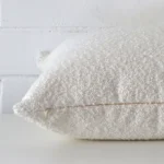 Square boucle cushion cover positioned flat to show seams. The white hue is shown between front and rear fabric panels.