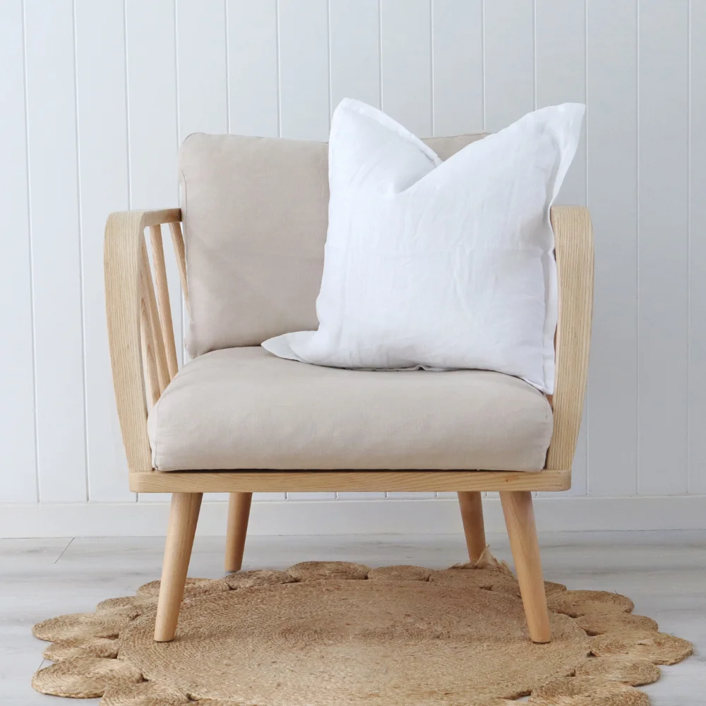 A white cushion on a modern chair that has a wooden frame.