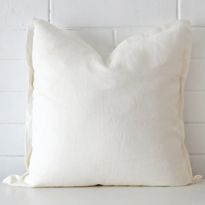 white-linen-cushion-cover-sc809-55 Bold square white cushion positioned in front of white brickwork. It has linen fabric.