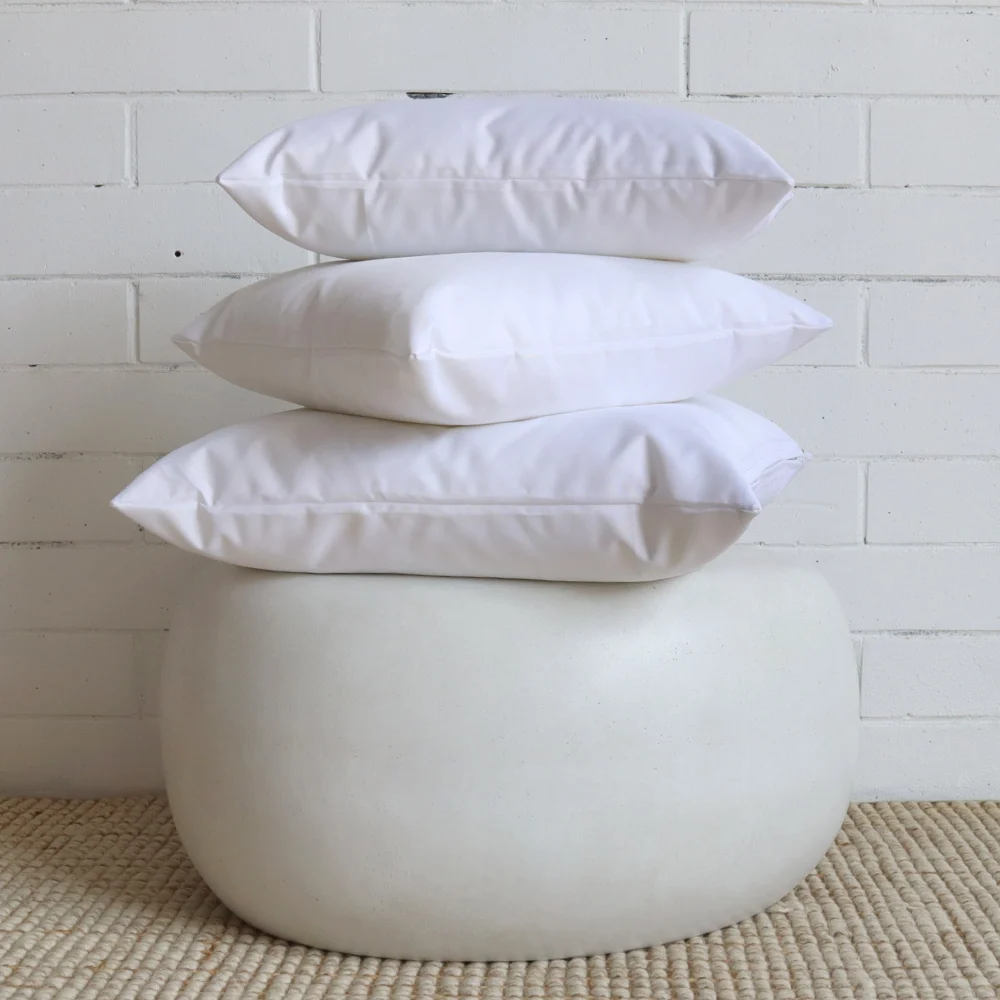 Three white outdoor cushions in a stack on top of a side table.