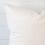 Close range image of white cushion. The large size and velvet material can be seen in detail.