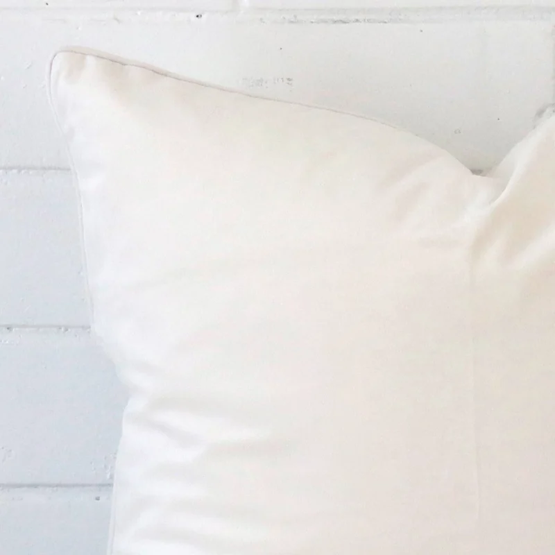 Close range image of white cushion. The large size and velvet material can be seen in detail.