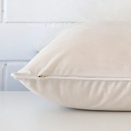 Large cushion cover in white colour sitting flat. The sideways viewpoint shows the seams of the velvet material.