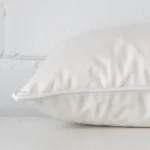 White cushion cover laid on its back side. The image shows a side-on view of the velvet material and its rectangle dimensions.