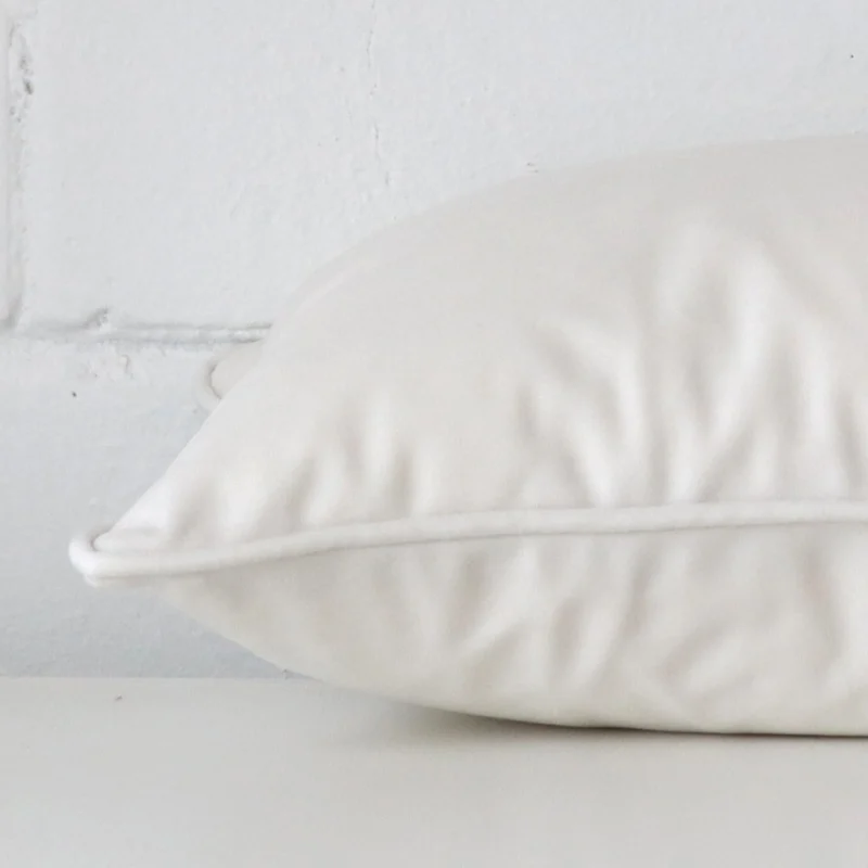 White cushion cover laid on its back side. The image shows a side-on view of the velvet material and its rectangle dimensions.