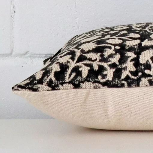 Side angle shot of designer square cushion cover. The floral style is shown along its seams.