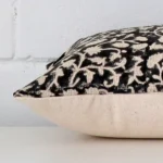 Floral cushion laid horizontally. This perspective shows the edge of the designer fabric and its rectangle shape.