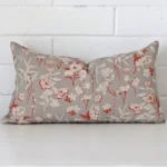 White wall with a floral grey cushion laying against it. It has a distinctive linen fabric and has a rectangle shape.