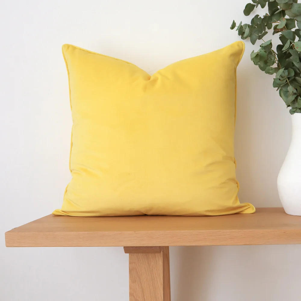 A yellow cushion sits against a white wall and on top of a bench seat.