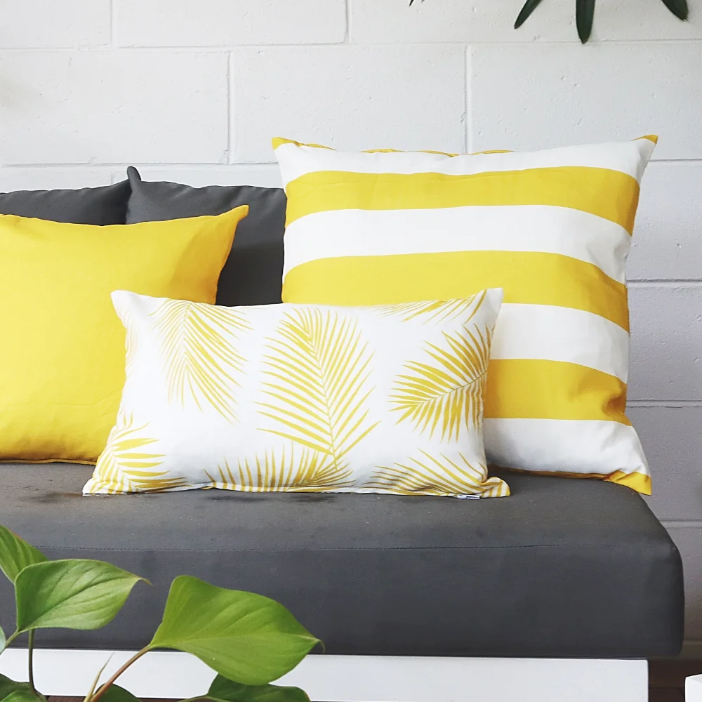 Three yellow outdoor cushions on a dark seat outside.