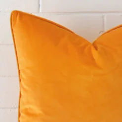 Focused view of square cushion cover. The shot shows details of its velvet material and yellow colour.