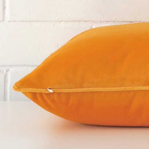Yellow cushion cover laid on its back side. The image shows a side-on view of the velvet material and its large dimensions.