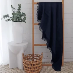 A black linen throw hanging on a wooden rack gives a white room an elegant look.