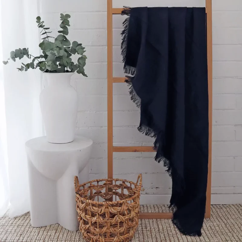 Black Linen Throw - TH814 A black linen throw hanging on a wooden rack gives a white room an elegant look.