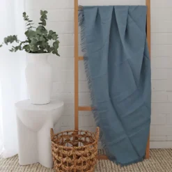 A stylish wooden rack in a white room with a blue linen throw hanging on it.