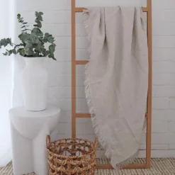 A soft natural linen throw hanging on stylish wooden rack.