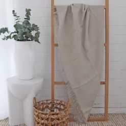 A wooden rack styled with a stone linen throw.
