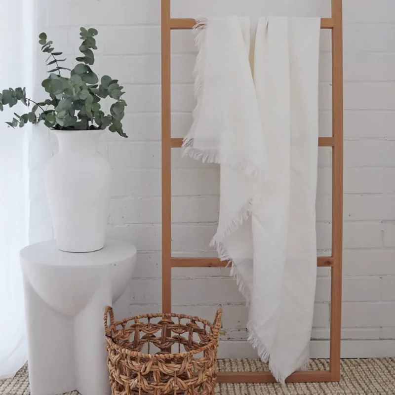 White Linen Throw - TH809 A wooden rack with a white linen throw hanging on it.