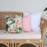 A couch styled with a set of 3 cushions including white, pink and floral designed outdoor cushions.