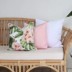 A couch styled with a set of 3 cushions including white, pink and floral designed outdoor cushions.