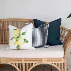 A set of 3 outdoor cushions including navy-coloured and lemon printed cushions styled on a couch creating a mediterranean style.
