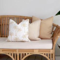 3 beige coloured outdoor cushions arranged beautifully on a couch.