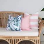 A set of 3 palm pink coloured outdoor cushions arranged beautifully on a couch.