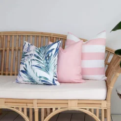 A set of 3 palm pink coloured outdoor cushions arranged beautifully on a couch.