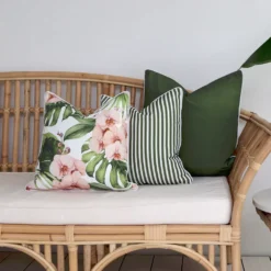 A set of 3 olive outdoor couch cushions arranged on a seat against a white wall.