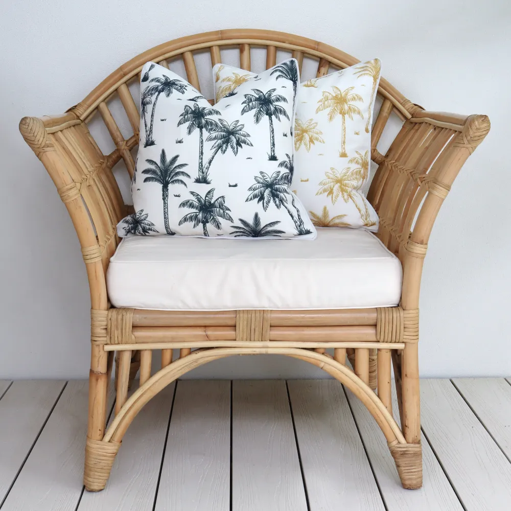 Two palm tree cushions styled on an outdoor armchair.