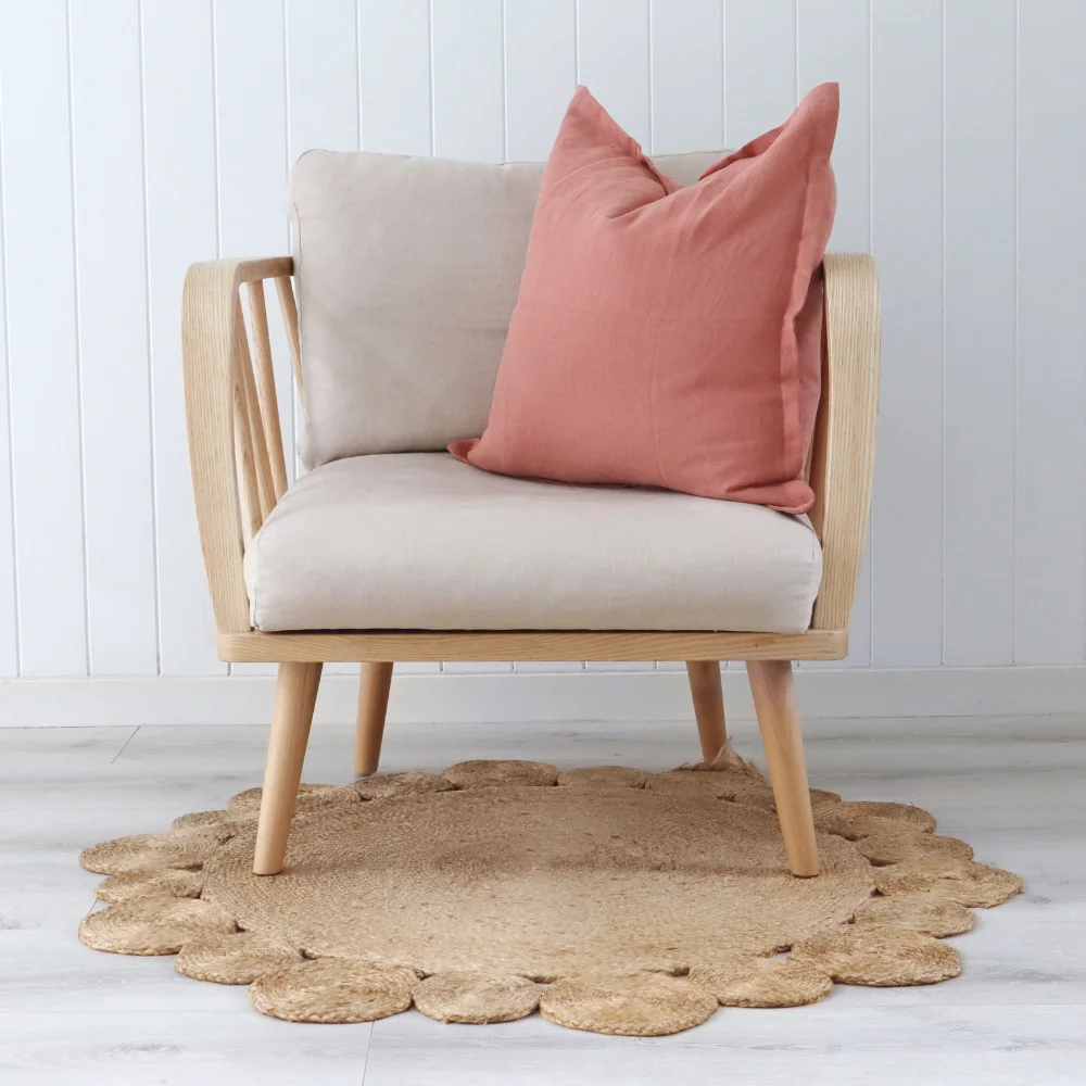 Peach cushions styled on a single light coloured armchair with wooden arms.