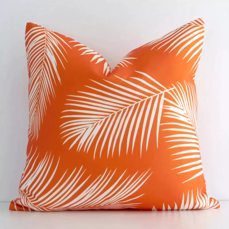 byron-palm-waterproof-orange-outdoor-cushion-cover---sc716-45 White wall with a palm-designed orange cushion laying against it. It has a distinctive outdoor fabric and has a square shape.