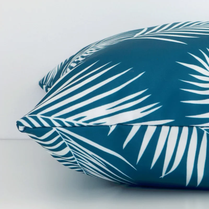 The seams of this outdoor square cushion cover in teal are shown. The image shows the palm design and how the panels are attached.