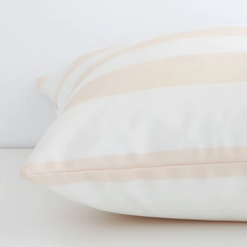 Enlarged image of the side of this beige outdoor cushion. The angle highlights how the large size and palm decorative finish are joined along the seam.
