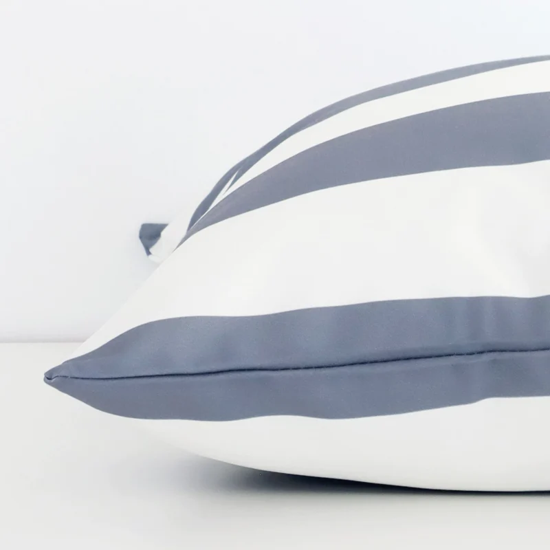 Side shot showing the seam of this large grey cushion that features a striped motif on its outdoor material.