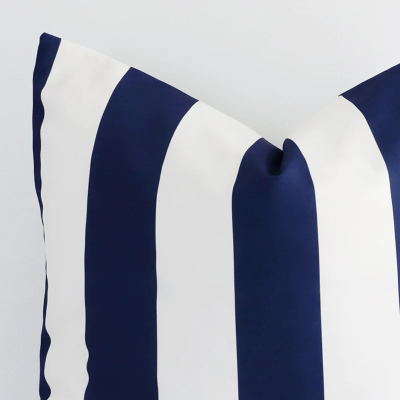 A close up shot showing the top left side of this large outdoor cushion cover. The navy tone and striped design are magnified.