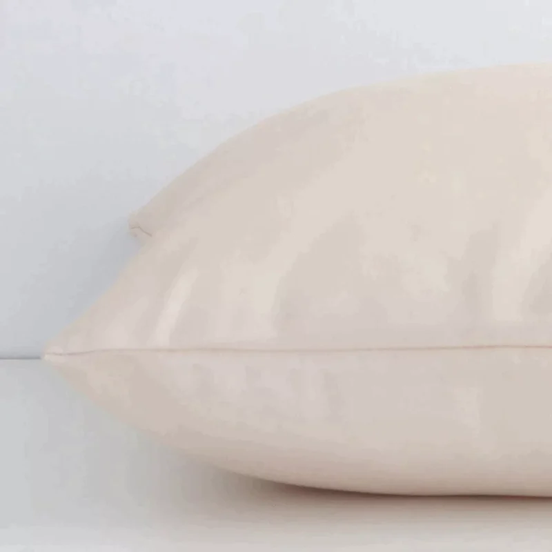 Square solid-coloured cushion in beige colour laying flat. The viewpoint highlights the seams of the outdoor fabric.