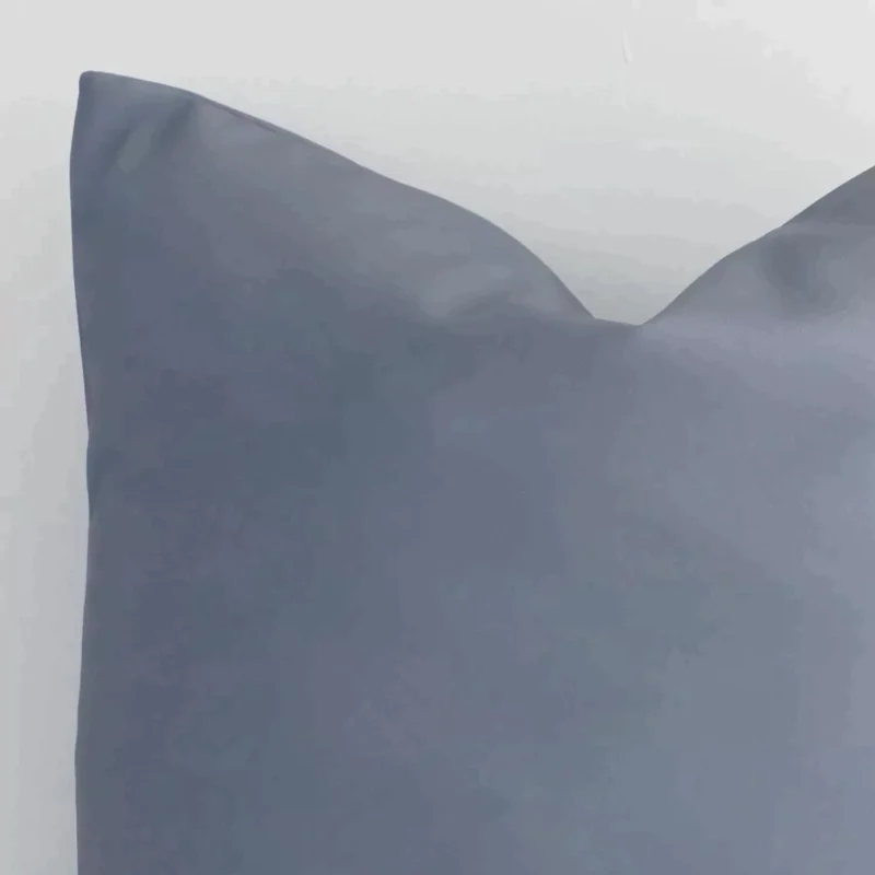 The corner of this outdoor square cushion cover is shown close up. The solid-coloured design and grey colour are shown in greater detail.