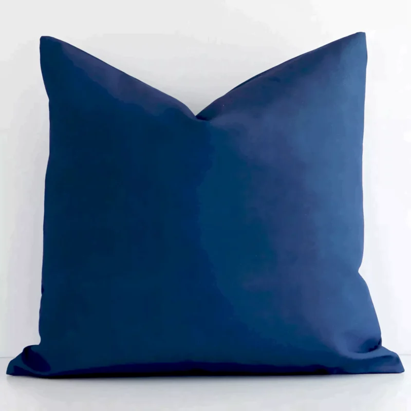caravan-peacock-blue-green-waterproof-outdoor-cushion-cover---sc577-45 A blue, solid-coloured cushion cover sits against a white wall. It is constructed from a superior looking outdoor material and has square shape.